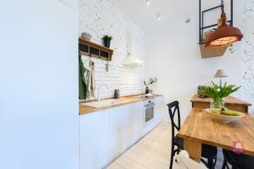 Aneks kuchenny z wyspą i jadalnią w mieszkaniu w kamienicy przy parku w Łodzi