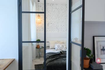 Sypialnia z przeszkleniem w mieszkaniu w kamienicy przy parku w Łodzi